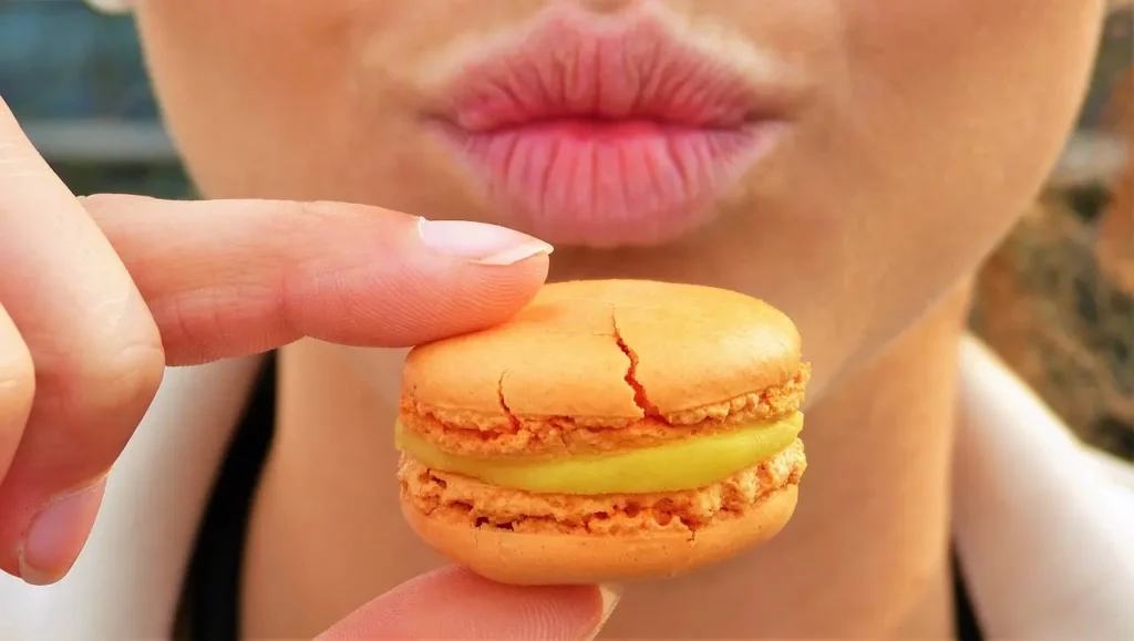 Femme qui souffre de la compulsion alimentaire et qui s’apprête à manger un macaron.